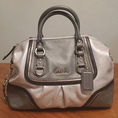 Ashley Spectator Leather Satchel Authentic, Tags Still On Style F17455 Silver Leather Looks Very Nice In Person, Pictures Don't Quite Capture The Metallic Sheen. Silvertone Hardware Height: 8" Width: 12" Depth: 4" Twin Handles 4" Drop Detachable Shoulder Strap Has Shoulder Pad At Center And Twin Swivel Dog Leash Trigger Clasps. Bottom Has Snaps Tabs That Will Store The Shoulder Strap When Unused. Interior Lined In Pink Satin Material. One Interior Zipper Pocket & One Open Pocket. Elegant Silver Bag With Branded Hardware, Designer Silver Bag With Handles, Classic Coach Silver Bag, Metallic Bags With Silver-tone Hardware, Elegant Silver Coach Bag, Designer Silver Bags With Silver-tone Hardware, Coach Silver Evening Bag, Silver Coach Evening Bag, Silver Coach Bag For Evening