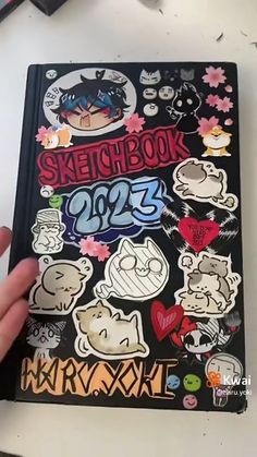 someone is holding up a notebook with stickers on the front and back cover that says sketchbook 2095