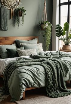 a bed with green comforter and pillows in a bedroom next to a large window