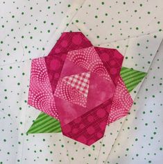 a pink and green flower sitting on top of a white table covered in polka dots