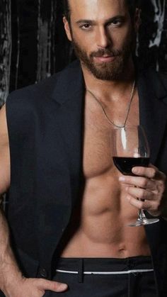 a shirtless man holding a glass of wine