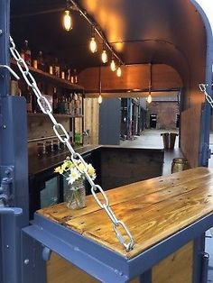 an outdoor bar with lights hanging from it's ceiling and wooden counter top in front of the bar