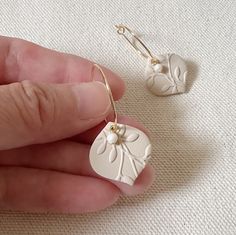 a hand holding a pair of white earrings