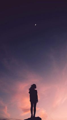 a person standing on top of a rock at sunset