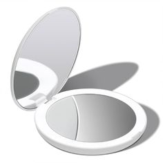 an open compact mirror sitting on top of a white table next to a shadowless wall