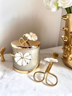 a pair of gold scissors sitting on top of a table next to a vase with flowers