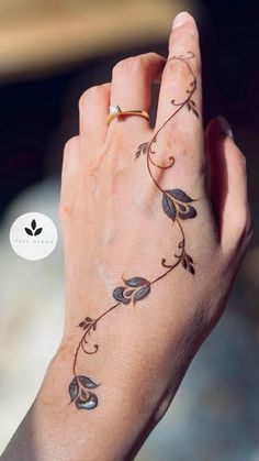 a woman's hand with a vine tattoo on her left wrist and the other arm