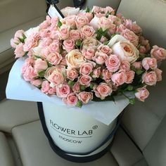 a bouquet of pink roses sitting on top of a white hat in the back seat of a car