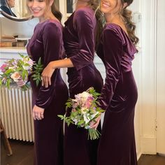 three bridesmaids in long purple dresses with flowers on their bouquets smiling at the camera