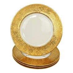 three gold plates stacked on top of each other in front of a white background,