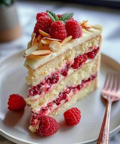 a piece of cake on a plate with raspberries and almonds