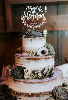 a three tiered cake with succulents and greenery on top