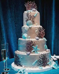 a three tiered cake decorated with sea creatures and seashells sits on a blue table cloth