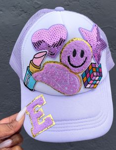 a person holding up a purple hat with patches on it