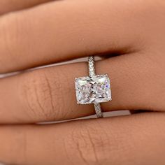 a woman's hand with a diamond ring on top of her finger and an engagement band