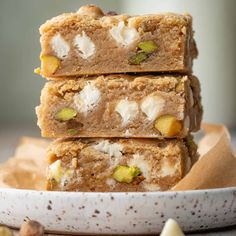 three pieces of food are stacked on top of each other in a white bowl next to some nuts