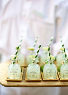 small glass bottles with green and white striped straws in them on a wooden tray