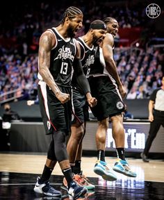 three basketball players standing on the court with their hands in each other's pockets