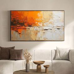 a living room with white couches and an orange painting on the wall above it