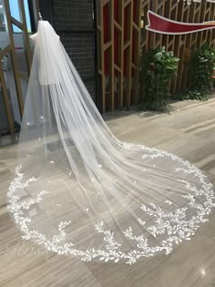 a wedding veil with white flowers on the floor in front of a wooden wall and window