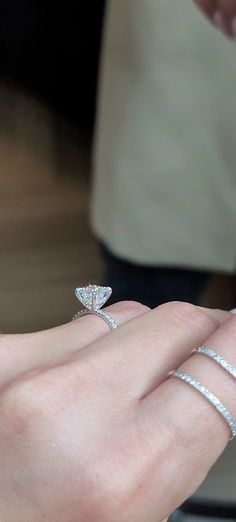 a close up of a person's hand holding an engagement ring