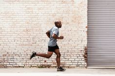 a man running down the street in front of a brick wall