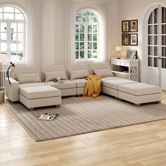 a living room filled with lots of furniture next to two large windows on top of a hard wood floor