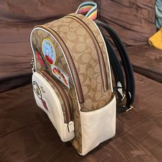 Signature Coated Canvas And Refined Pebble Leather Inside Zip And Multifunction Pockets Double Zip Closure, Fabric Lining Handle With 2 1/4” Drop Outside Zip Pocket Adjustable Shoulder Straps 10 3/4” (L) X 12 1/2” (H) X 4 3/4” (W) Coach X Peanuts Style No. C4115 White Coach Backpack For Everyday Use, White Coach Backpack For Travel, Casual Coach Bags For School, Casual Coach Backpack For Travel, Everyday White Coach Backpack, Coach Leather Backpack With Adjustable Strap, Coach Brown Standard Backpack, Coach Backpack With Adjustable Strap, Coach Coated Canvas Backpack