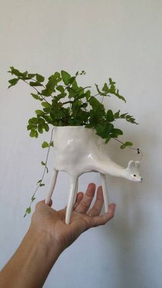 a hand holding a planter shaped like a giraffe