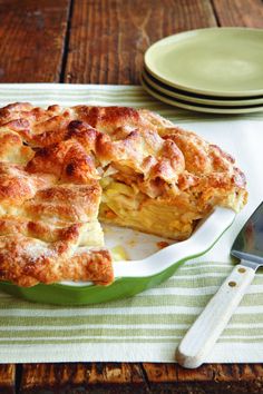 a pie sitting on top of a white plate next to a knife and fork in front of it