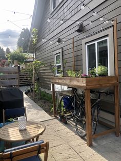 a bicycle is parked next to a table with flowers on it and lights strung from the roof