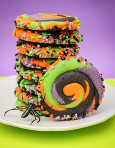 a stack of decorated cookies sitting on top of a white plate next to a purple and green background