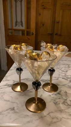 three martini glasses filled with chocolates on top of a marble counter