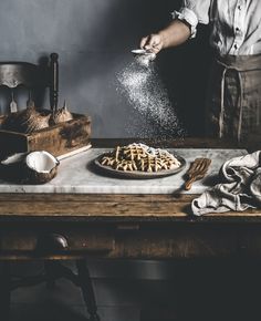 a person is sprinkling sugar onto a pie on a table with other items