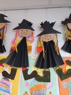 three paper dolls with black hats and long hair are hanging on the wall next to colorful papers