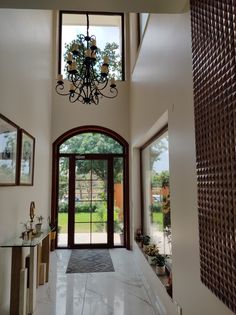 a large foyer with a chandelier hanging from it's ceiling and windows