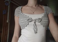 a woman wearing a white top with a crocheted bow on the front and side