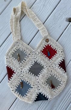 a crocheted bag with red, white and blue designs on the front hanging from a hook