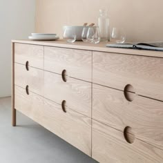 a wooden dresser with drawers and plates on top