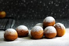 powdered sugar coated doughnuts sitting on top of a white tablecloth next to an oven rack