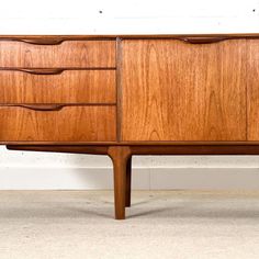 a large wooden dresser with drawers on the top and bottom, against a white wall