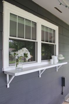 two vases with flowers are sitting on a window sill in front of a house