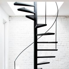 a black spiral staircase in a white room