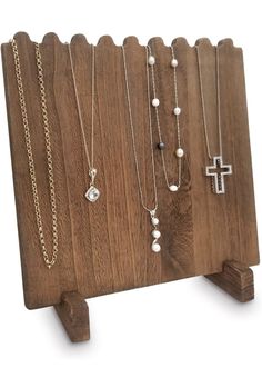 a wooden stand with several different necklaces hanging from it's sides and a cross on the other side