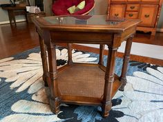 a wooden table with a glass top on a rug in front of a dresser and chair