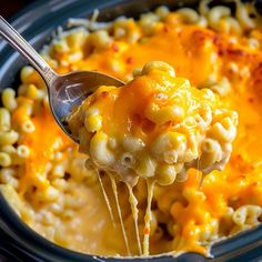 a spoon full of macaroni and cheese being lifted from the crock pot