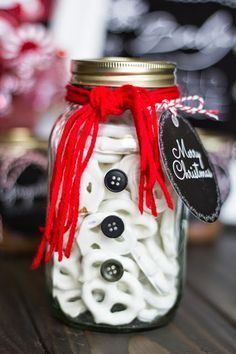 a mason jar filled with white buttons and red ribbon tied around the top, sitting on a wooden table