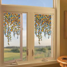 a room with two windows that have stained glass designs on the window sill, and a table in front of them