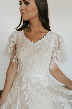 a woman wearing a wedding dress with sheer sleeves