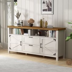 a living room with white walls and wooden floors, a large book shelf on top of the sideboard